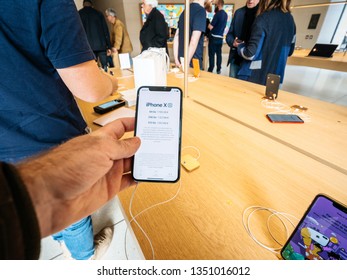 Paris, France - Mar 19 2019: Man POV Personal Perspective Holding IPhone XS Inside The New Apple Store Champs-Elysees - French Flagship Store Building Display Showing Phone Prices In Euros