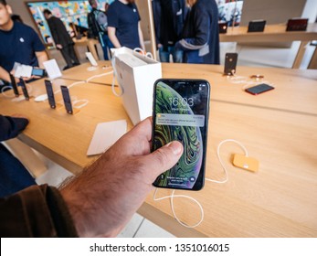 Paris, France - Mar 19 2019: Man POV Personal Perspective Holding IPhone XS Inside The New Apple Store Champs-Elysees Shopping For New Smartphone With Customers Silhouettes In Background 