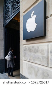 Paris, France - Mar 19, 2019: Woman enters the store with Apple Computers logotype insignia next to the entrance of the iconic Apple Store on Champs Elysee - tilt shift lens used