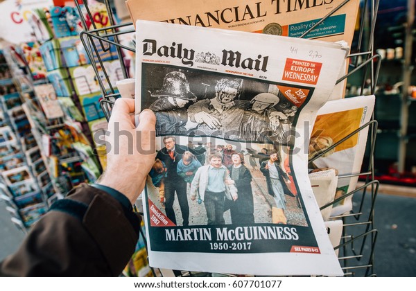 PARIS, FRANCE - MAR 23, 2017: Man purchases Daily\
Mail newspaper featuring James Martin Pacelli McGuinness tribute.\
He was an Irish politician who was the deputy First Minister of\
Northern Ireland