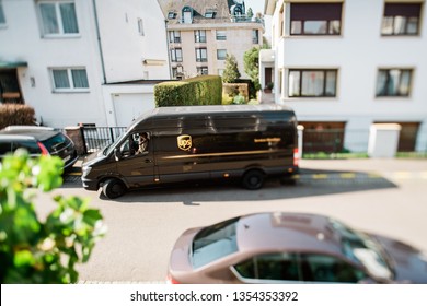 Paris, France - Mar 27, 2019: View from above of leaving brown UPS delivery parcel van on French residential street - tilt-shift lens used shallow focus focus on driver speaking on the phone