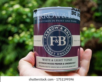 Paris, France - Mar 3, 2020: Man Hand Holding Against Green Background New Pot With Farrow And Ball White And Light Toned Wood Primer And Undercoat Before Renovating In English Style The House