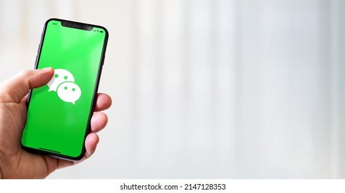 Paris - France - March 15, 2022 : Hand holding iphone smartphone with WeChat logo. Horizontal banner