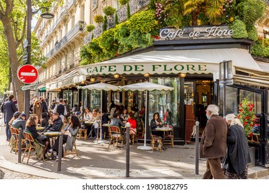 Paris, France - May 19, 2021: Day after lockdown due to covid-19 in a famous Parisian cafe. 2 waiters wear surgical masks