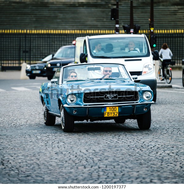 PARIS, FRANCE - MAY 21, 2016:\
Couple in vintage Mustang driving relaxed on Paris street\
coblestone