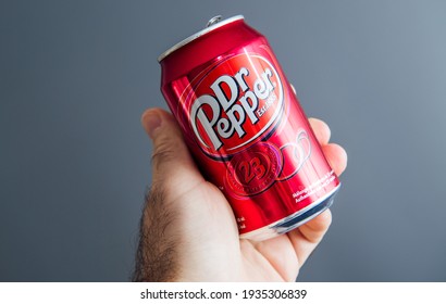 Paris, France - May 3, 2020: Hero object holding pov male hand holding aluminum can of Dr Pepper manufactured by Dr Pepper Snapple Group soft sweet drinks - isolated against gray background