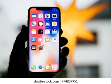 PARIS, FRANCE - NOV 10, 2017: Man Holding The New Apple IPhone X 10 Display With Yellow Star Bokeh Background Featuring All Home Apps On The Retina Screen 