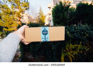 Paris, France - Nov 16, 2018: POV Personal Perspective Male Hand Holding Showing Amazon Prime Cardboard With Festive Holiday Scotch Tape - Defocused City Background