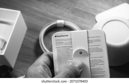 Paris, France - Nov 17, 2020: Man Unboxing The Latest Apple Computers HomePod Mini Smart Speaker Developed By The Computer Firm Reading The Instructions - Black And White