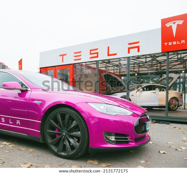 Paris, France - Nov 29, 2014: New fuchsia\
colored Tesla Motors Model S car parked near a glass modern\
dealership with car inside - open doors of the electric car\
manufacturer in offices\
worldwide