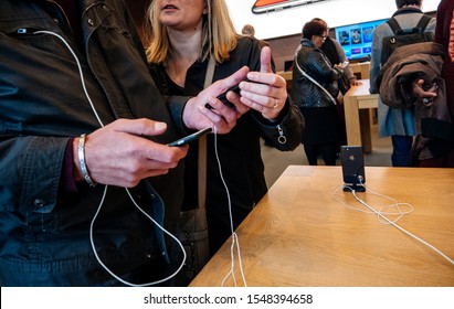 Paris, France - Nov 3, 2017: Side View Of Young Couple Admiring Inside Apple Store The Latest Professional IPhone Smartphone Manufactured By Apple Computers Comparing With Older Model Android Phone