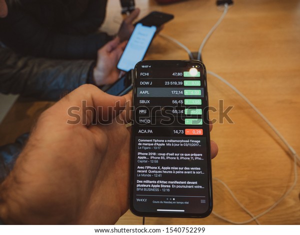Paris, France - Nov 3, 2017: Customers admiring\
inside Apple Store the latest professional iPhone X smartphone\
manufactured by Apple Computers with stock price quotation for Dow\
J SUX NKE YHOO, FCHI
