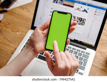 PARIS, FRANCE - NOV 5, 2017: POV Of Woman Testing The New Apple IPhone X 10 Smartphone (with Chroma Key Backgrounds) In Creative Room Environment Table  With Facebook Social Network Running On Laptop