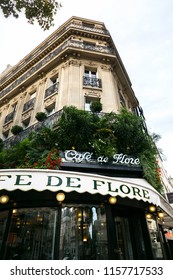 Paris, France - November 01, 2017: The Famous Cafe De Flore. Saint-Germain Boulevard. Signboard Of The Cafe Decorated With Green Plants. Autumn Paris. Typical Parisian Houses With Balconies. 