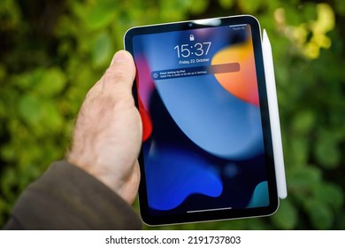 Paris, France - Oct 21, 2021: POV Male Hand Holding New Smart Tablet IPad Pro Mini With Apple Pencil - Home Screen With Finish Setting Up Ipad Message - Green Garden Background