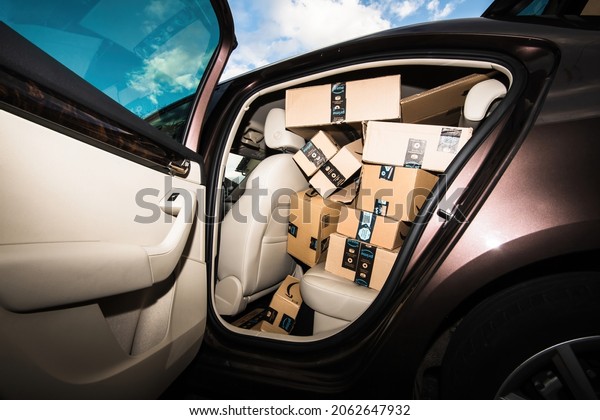 Paris, France - Oct 21, 2021: Open luxury car door
with leather interior and multiple Amazon prime cardboard parcel
boxes - part time delivery job from the Seattle tech giant founded
by Jeff Bezos