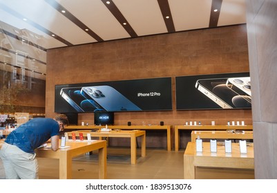 Paris, France - Oct 23, 2020: Apple genius employee near the new iPhone 12 and iPhone 12 Pro on display during launch day in Apple Store. Latest 5G smartphones go on sale worldwide.