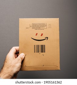 Paris, France - Oct 29, 2018: POV Male Hand Holding Amazon Prime Parcel Envelope With Smile Logo And Add Red Eyes To Form A Smiling Human Character