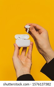 Paris, France - Oct 30, 2019: Woman Setting Removing From Charging Case Unboxing New Apple Computers AirPods Pro Headphones With Active Noise Cancellation For Immersive Sound Yellow Tech Background