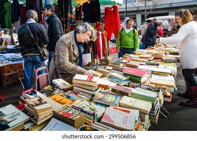 PARIS, FRANCE - OCTOBER 5, 2014: Women Check The Table Of Used Books At A Flea Market In The Historic Marche D' Aligre In The Bastille District.