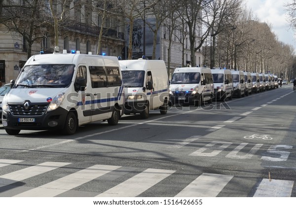 Paris / France - Police vehicles driving in\
line on an empty avenue in Paris,\
France