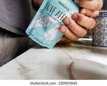 Paris, France - Sep 13, 2022: POV Male Hand Holding Pouch With Hardys Love Affair Kalb Und Pute Wet Cat Food - Modern Kitchen Background Preparing To Feed The Pet Cat Animal