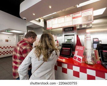 Paris, France - Sep 21, 2022: Customers At The Counter Reading The Menu Above Five Guys American Fast Food Restaurant Chain With Focused On Hamburgers, Hot Dogs, And French Fries, And Headquartered In