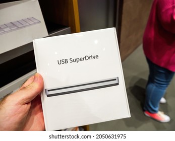 Paris, France - Sep 24, 2021: Male Hand Holding Inside Apple Store Almost Vintage USB SuperDrive Cd Reader For Apple Computers - Imac's, Macbook Pro, Mac Pro