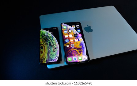 PARIS, FRANCE - SEP 25, 2018: Two new iPhone Xs and Xs Max smartphone model by Apple Computers close up on laptop MacBook pro closed lid. Newest golden Apple iPhone 11 mobile phone device 