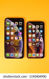 PARIS, FRANCE - SEP 27, 2018: Apple Computers iOS 12 home screen on iPhone Xs and Xs Max as hero object on bright glamorous modern neon pop orange background - smartphone telephone with OLED display