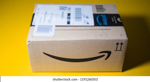 PARIS, FRANCE - SEP 28, 2018: Front view of new Amazon Cardboard box against yellow background smile log- tilt-shift lens