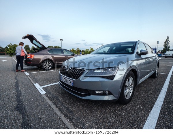 Paris, France - Sep 5, 2019: Large IKEA\
furniture parking with two Skoda cars Octavia and Superb parked in\
the evening woman loading goods in\
trunk