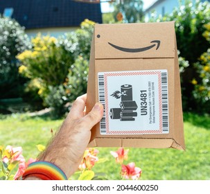 Paris, France - Sep 8, 2021: POV Male Hand Holding Package Of Amazon Prime Cardboard Package With UN3481 Sticker Norme Lithium Batteries Are Dangerous Goods And, As Such, Require Special Packaging