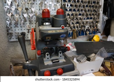 Paris, France - Sept. 2020 - Machine-tool For Key Cutting And Metalworking, In Front Of An Impressive Key Rack, On A Workbench Cluttered With Various Materials, In A Craftman Shoemaker's Shop