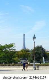 Paris, France - September 25 2021 -  An Unidentified Couple Wearing Masks Walk On A Street With A View Of The Eiffel Tower (known As The Tour Eiffel In French).  Image Has Copy Space.