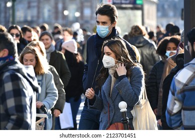 Paris, France-02 13 2022:Couple Of Young Adults Wearing Protective Face Masks In A Crowded Street Of Paris, France During The Global Coronavirus Epidemic.