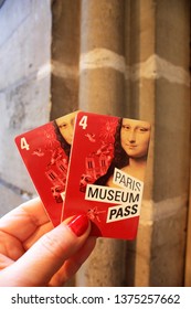  PARIS, FRANCE-18 April, 2018: The Female Hand Holds Two Cards  Paris Museum Pass For Four Days  Against The Background Of A Stone Wall. Copy Space