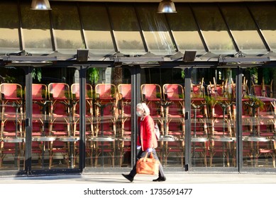 PARIS – MAY 18, 2020: A Woman Wearing A Mask Walks In Front Of A Restaurant Closed Because Of Covid-19. The Restaurant Industry Has Suffered Huge Sales And Job Losses Because Of The Covid-19 Outbreak.