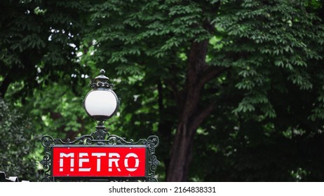 Paris metro sign on a lamppost - against a background of dense green foliage