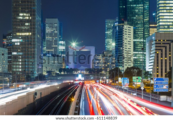 Paris night cityscape with modern buildings in\
business district La Defense with dynamic street traffic and car\
lights. Glass facade skyscrapers. Concept of economics, finances.\
Copy space. Toned
