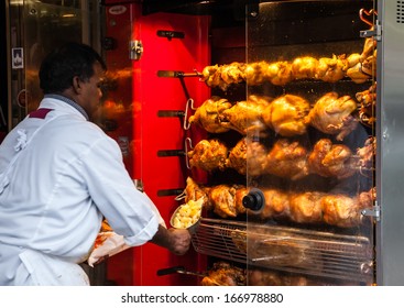 PARIS - NOV 30: Unidentified butcher sells traditional roasted chicken and potatoes near the entrance to the butcher shop in the city center on November 30, 2013 in Paris, France.