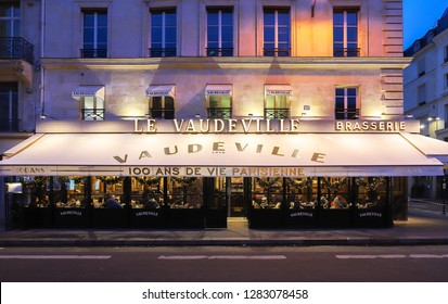 Paris,France-January 12, 2019: The Traditional French Brasserie Le Vaudeville At Night. It Is Located Near Brogniart Palace In Paris, France. Inscription In French On Sign: 100 Years Of Parisian Life.