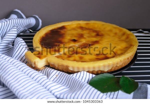  Parisian Flan (French Custard Pie) Classic tart.
Baked confectionery cream in shortbread dough crust. Pie and two
mini pies on dark background with leaves and light stripes textile.
Sliced