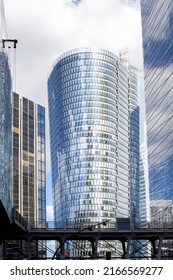Paris-la-Defense, France - June 12, 2022: Curved shaped office buildings with glass facade. Business district. Evening light. blue sky.