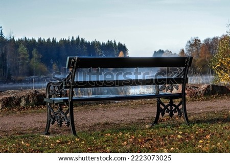 A park bench by the river, the fog is rising early in the morning.