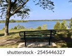 The park bench overlooking the lake in the park on a sunny day.