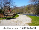 Park bench sits empty alongside a walking path at Settlers Park in Sheboygan Falls, Wisconsin 