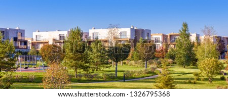 Park and gardens in modern town,  landscape of green public place with residential buildings. Scenic panorama of townhouses and trees in summer. Concept of habitat, house landscaping, life and nature