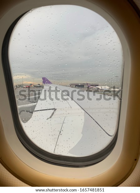 Parked aircraft entire window’s view of the wing,\
winglet and airport