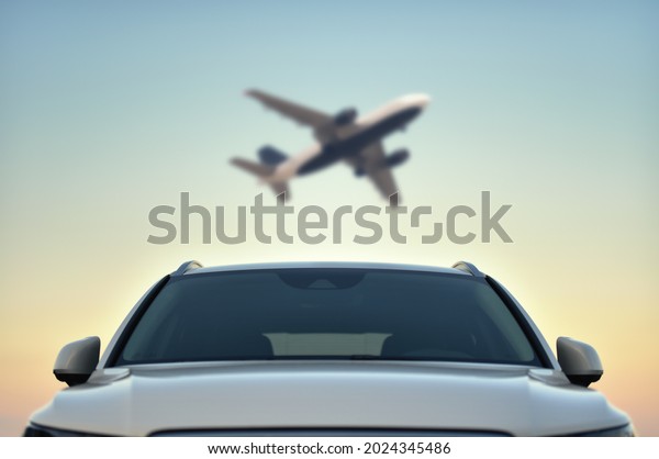 Parked Car in airport with taking off airplane\
on sky background. Transfer\
concept.